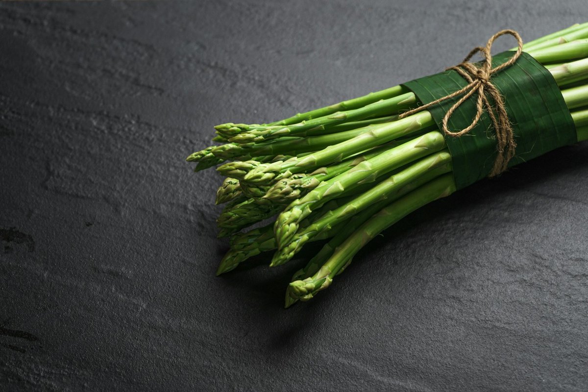 Botte d'asperges vertes liée posée sur une ardoise