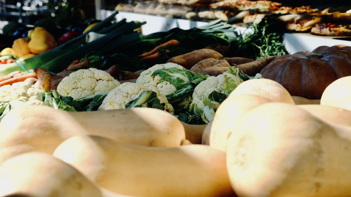 Étal de marché à l'automne : butternuts au premier plan, choux-fleurs et poireaux derrière