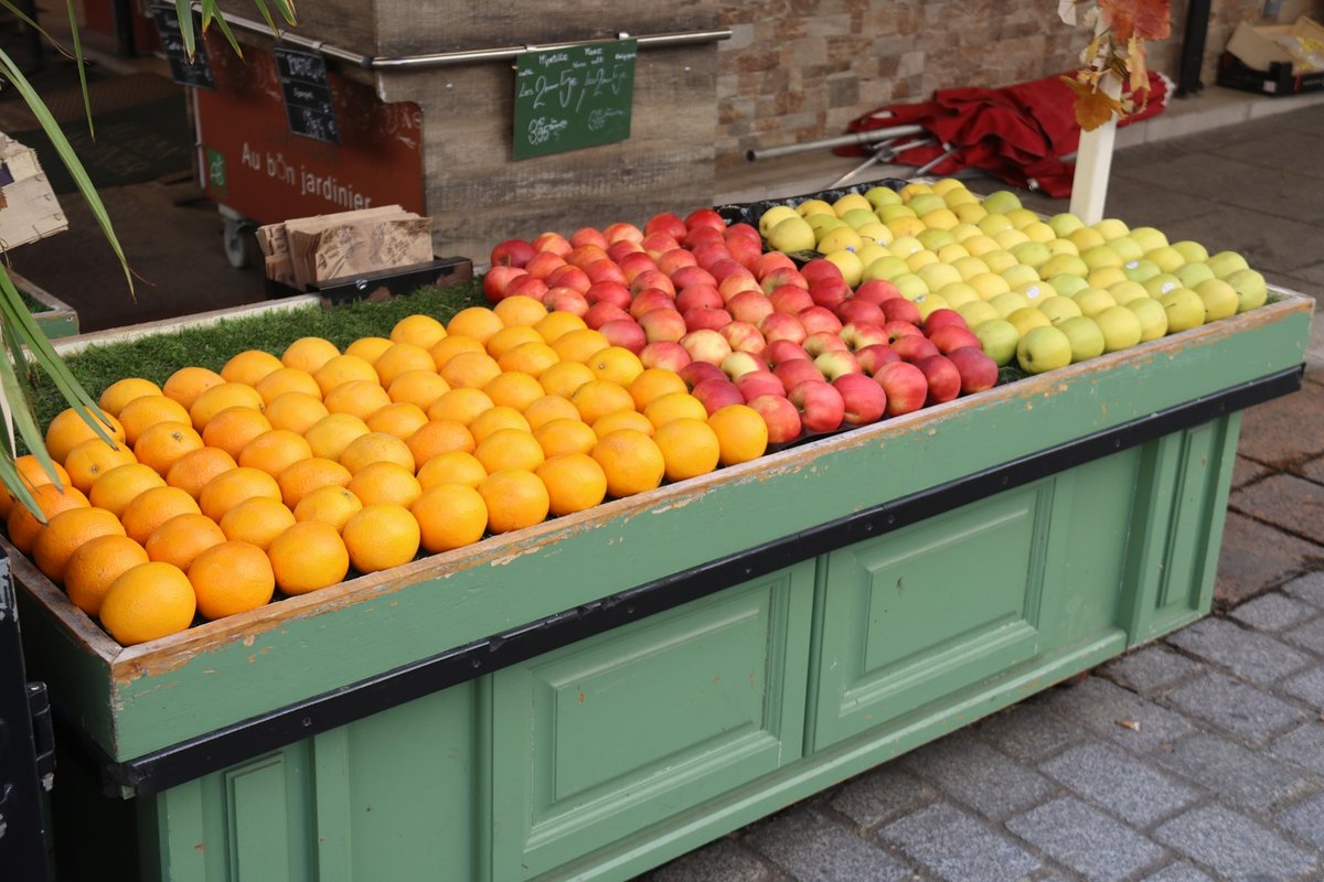 Étal de fruits en bois peint en vert : pommes et oranges avec leurs prix