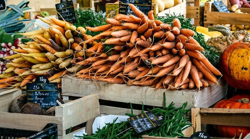 Bottes de carottes avec leurs fanes sur l'étal d'une halle couverte